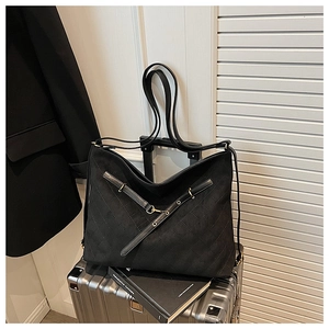 Close-up of black quilted tote bag with cross straps on a metallic suitcase