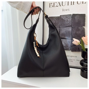 Detail of black pebbled leather hobo bag with colorful beaded tassel and golden buckle