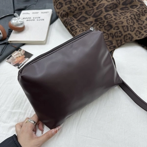 Détail d'une pochette en simili cuir marron foncé avec fermeture éclair argentée