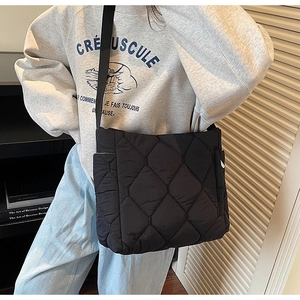 Detail of black quilted puffer tote bag showing geometric diamond texture and side pocket