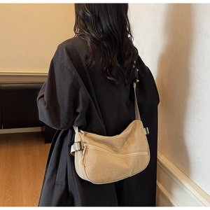 Close-up of beige nylon crescent bag with adjustable wide strap and zipper detail