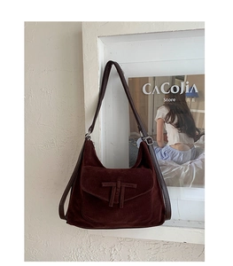 Close-up of vintage dark reddish-brown suede hobo bag with unique T-knot flap and leather strap