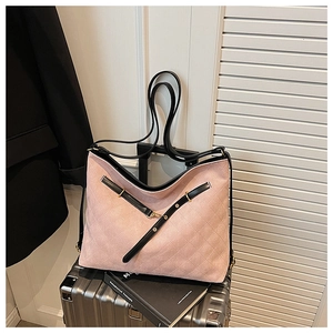 Pink quilted tote bag with black leather trim and gold hardware on luggage