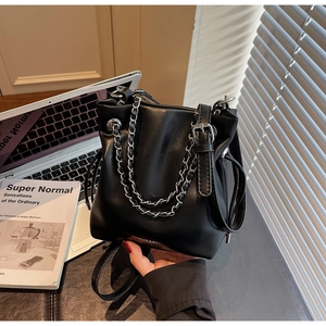 Detail of black PU leather bucket bag with silver chain decor and adjustable strap