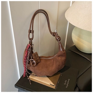 Détail du sac croissant en daim marron foncé avec poignée à nœud et charms créatifs
