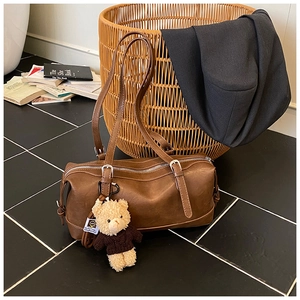 Detailed view of the brown leather Boston bag with a cute bear plush keychain accessory
