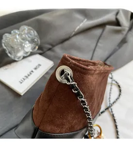 Détail de la bandoulière chaîne sur le sac hobo en daim marron avec cuir contrasté