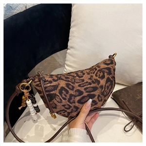 Detailed view of leopard print crescent bag with leather strap and beaded charm accent