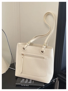 Detail of cream white tote bag featuring lychee grain texture and golden metal hardware
