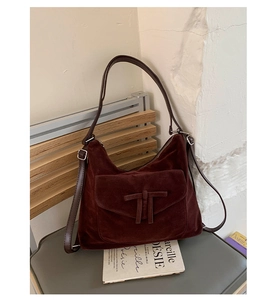 Detailed close-up of dark burgundy faux suede crossbody bag with decorative front knot