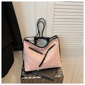 Pink quilted tote bag on silver suitcase featuring contrast black straps and gold buckles