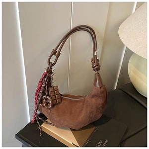 Détail d'un sac hobo demi-lune en daim marron avec breloques chocolat et bretzel