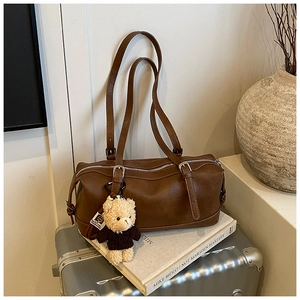 Detail of dark brown vintage Boston bag with bear charm on a retro suitcase