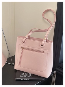 Detail of pink pebbled leather tote bag with functional front zipper pocket and gold eyelets