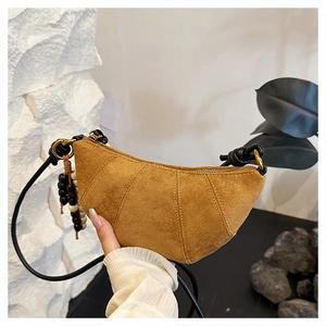 Close-up of yellow croissant crossbody bag with wooden bead detail and golden hardware