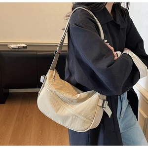 Detail of light beige crescent bag showing double zippers and wide adjustable strap