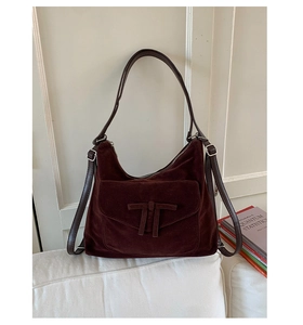 Close-up of brown suede shoulder bag showing matte texture and decorative knot detail