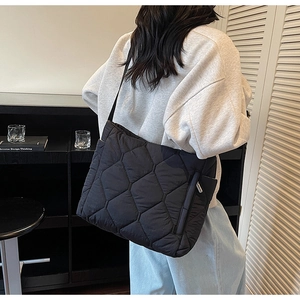 Detail of black quilted puffer tote bag with hexagonal honeycomb stitching and fabric strap