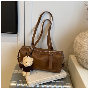 Detail of vintage brown pillow bag featuring a cute teddy bear charm on an adjustable strap
