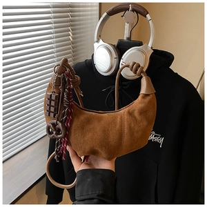 Détail d'un sac demi-lune en daim marron avec des charms chocolat et bretzel