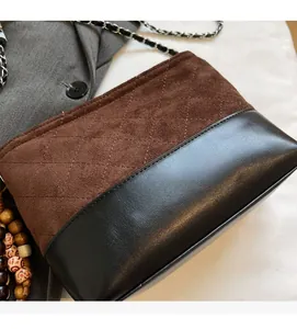 Détail de la couture en daim marron matelassé et cuir noir sur le sac à bandoulière