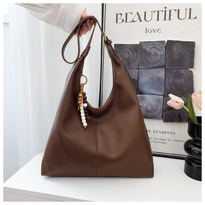 Detail of dark brown tote bag with lychee texture leather and a retro wood bead charm