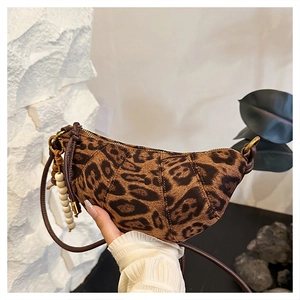 Detail of leopard print crescent bag featuring soft suede texture and beaded tassel