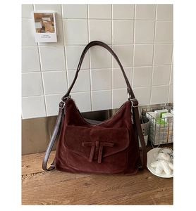 Macro view of dark brown suede shoulder bag featuring a minimalist bow decoration