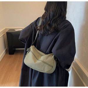 Detail of olive green crescent nylon bag featuring zipper pocket and adjustable strap