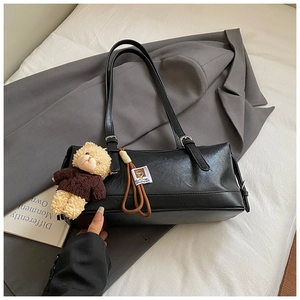 Detail of black faux leather shoulder bag with a cute plush bear pendant accessory