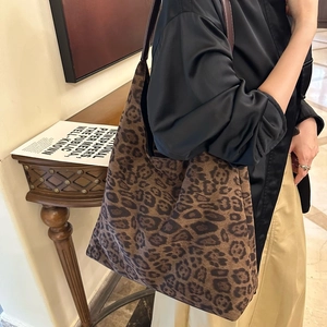 Gros plan détaillé du sac cabas en daim léopard avec anses en cuir pour un style décontracté