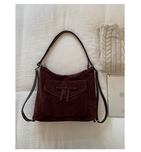 Detail of vintage dark brown nubuck shoulder bag with knotted flap on beige linen fabric