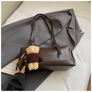 Detail showing deep brown faux leather texture and cute plush bear charm on the bag