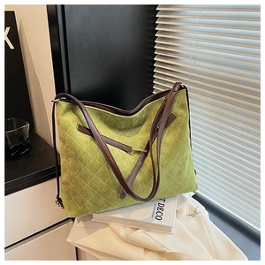 Detail of green quilted tote bag with brown leather trim and matte texture finish