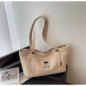 Detailaufnahme der beigen Canvas-Tasche mit Mädchen-Stickerei und Docile girl Schriftzug