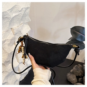 Detail of black suede crescent bag with radial stitching and wooden bead tassels