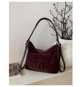 Detail of burgundy suede hobo bag featuring decorative bow and elegant leather strap