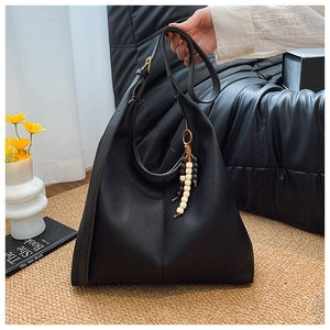 Detail of black pebbled leather hobo bag with wood bead tassel and adjustable strap