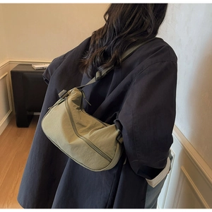 Detail of olive green crescent crossbody bag with adjustable strap worn by model