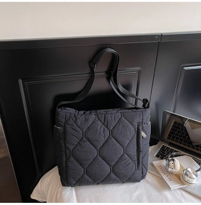 Close-up of black quilted puffer tote bag with diamond stitching and adjustable strap