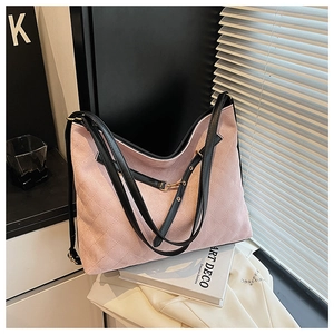 Detailed close-up of pink quilted suede handbag with black straps and gold hardware