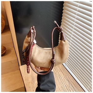 Détail du sac croissant en daim camel avec gland tressé et poignée en cuir marron
