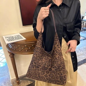 Détail de la texture suédée léopard et de la poignée en cuir marron du sac seau