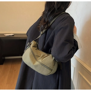Close-up of olive green nylon crescent bag showing the adjustable wide fabric shoulder strap