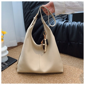 Detail of cream large tote bag with lychee texture and wooden bead tassel decoration