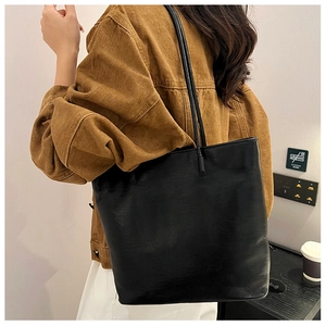 Detailed texture of black leather tote bag worn on shoulder for daily commute style