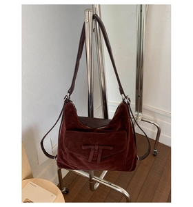 Detail of dark red suede shoulder bag with bow decoration and metal zipper closure