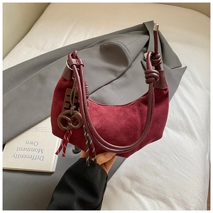 Détail du sac demi-lune en daim bordeaux avec bandoulière nouée et charms créatifs