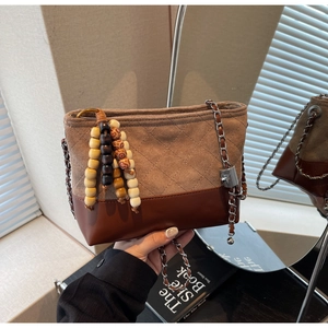 Detail of vintage quilted brown suede bucket bag with wooden bead fringe and chain strap