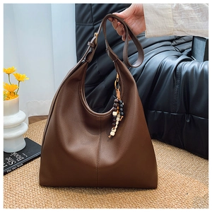 Detail of dark brown lychee leather hobo bag with wood bead tassel and metal hardware